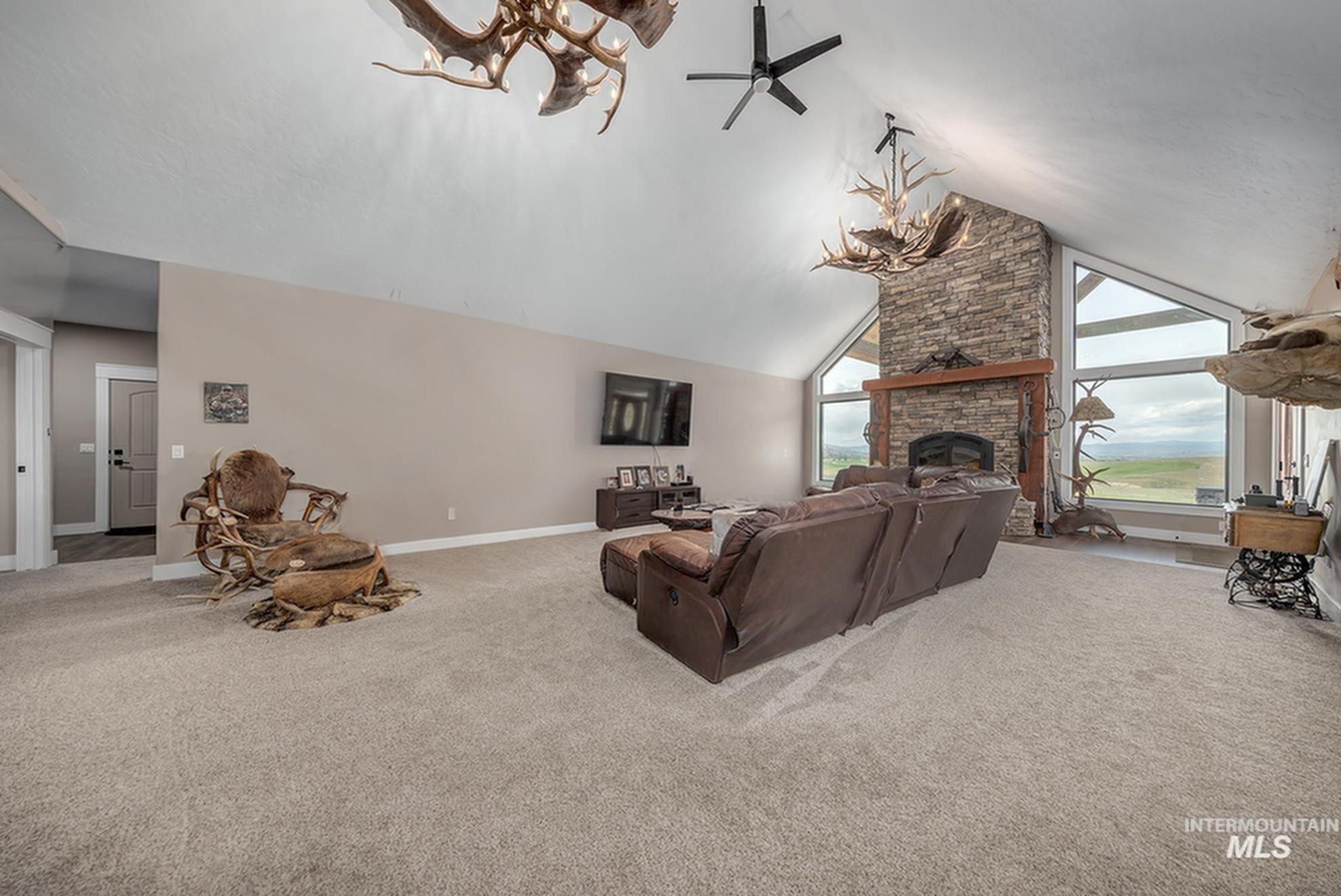 10228 Payette Heights Road Payette, ID 83661 - Photo 6 of 50 Great room featuring a vaulted ceiling, stone-clad fireplace with a wood mantel, expansive picture windows, and recessed lighting