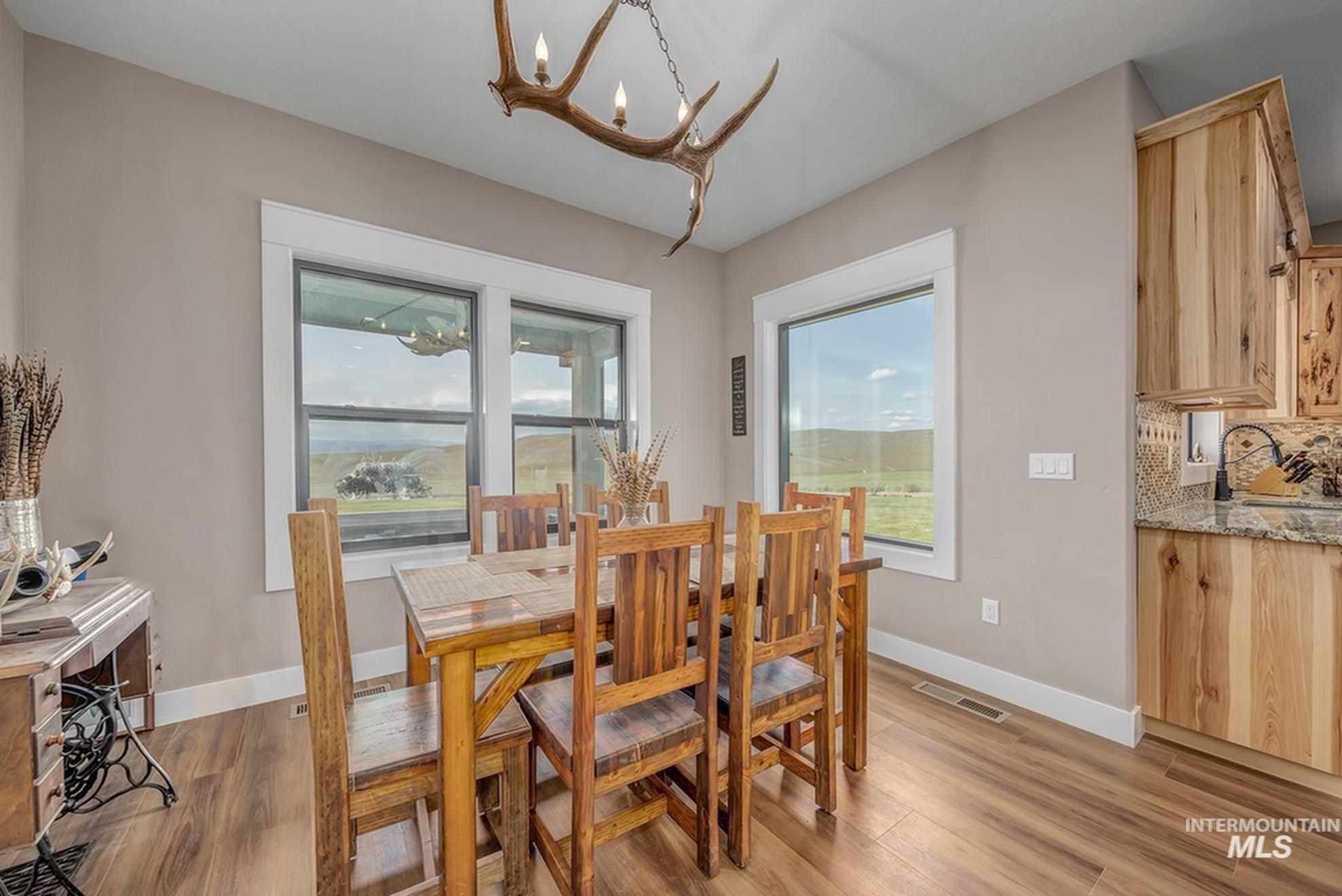 10228 Payette Heights Road Payette, ID 83661 - Photo 7 of 50 Dining area featuring wood-finish flooring, a large window with exterior scenery, a unique antler chandelier, and warm neutral wall tones