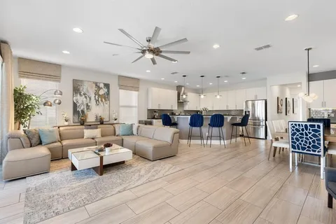a living room with furniture kitchen view and a large window