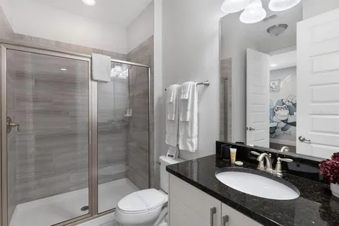 a bathroom with a granite countertop sink toilet a mirror and shower
