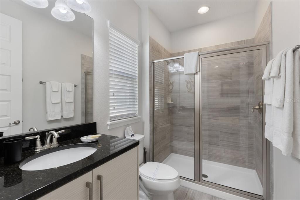 1036 Castle Pines Court Reunion, FL 34747 - Photo 27 of 50 a bathroom with a granite countertop sink toilet and shower