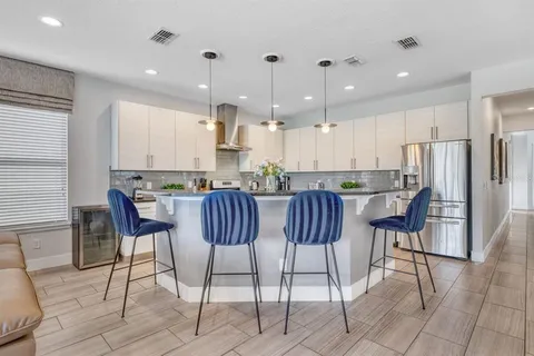 a view of kitchen with stainless steel appliances granite countertop dining table chairs cabinets and a window