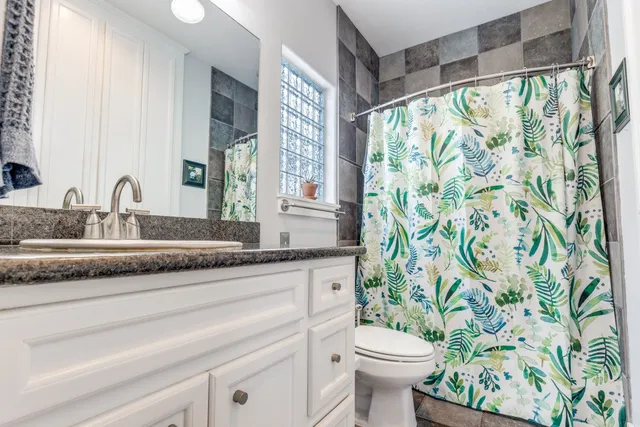 a bathroom with a granite countertop sink a toilet and a mirror
