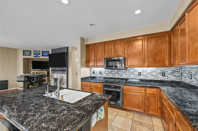 a kitchen with stainless steel appliances granite countertop a stove top oven a sink dishwasher a dining table and chairs with wooden floor