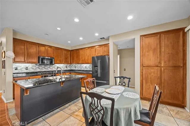 a kitchen with stainless steel appliances granite countertop a refrigerator a stove top oven a dining table and chairs