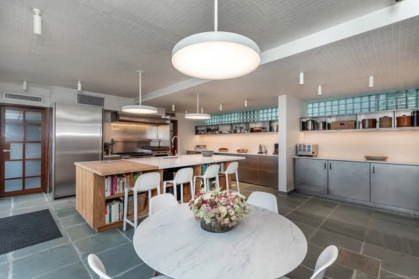 a kitchen with stainless steel appliances kitchen island granite countertop a table chairs and a refrigerator