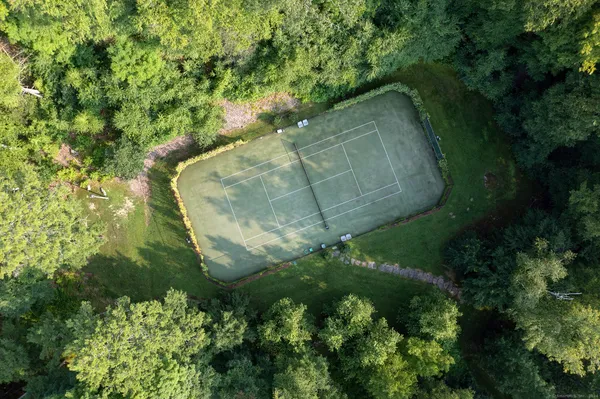 an aerial view of a residential houses with outdoor space and trees all around