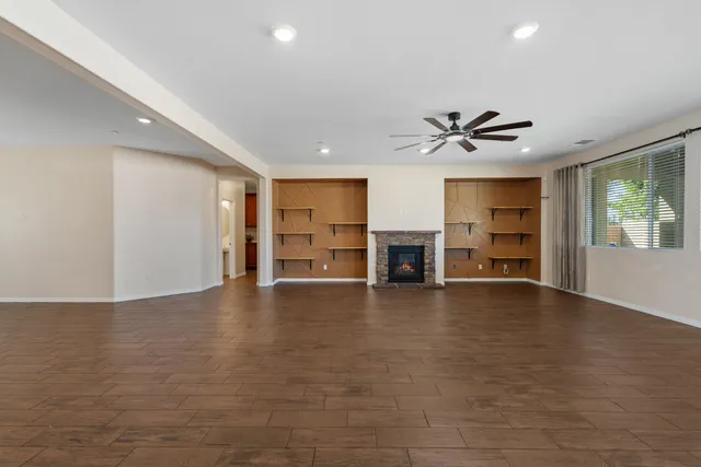 a view of a livingroom with a fireplace a ceiling fan and windows