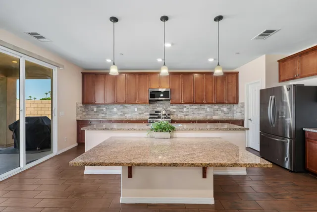 a kitchen with stainless steel appliances granite countertop a refrigerator a sink a stove and a wooden floors