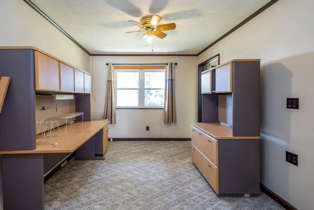 an empty room with windows and chandelier fan