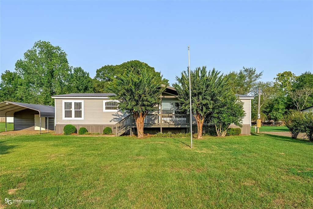 a view of a house with a big yard and large trees