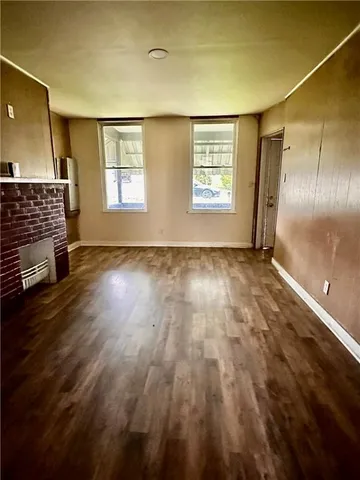 a view of an empty room with glass door and wooden floor
