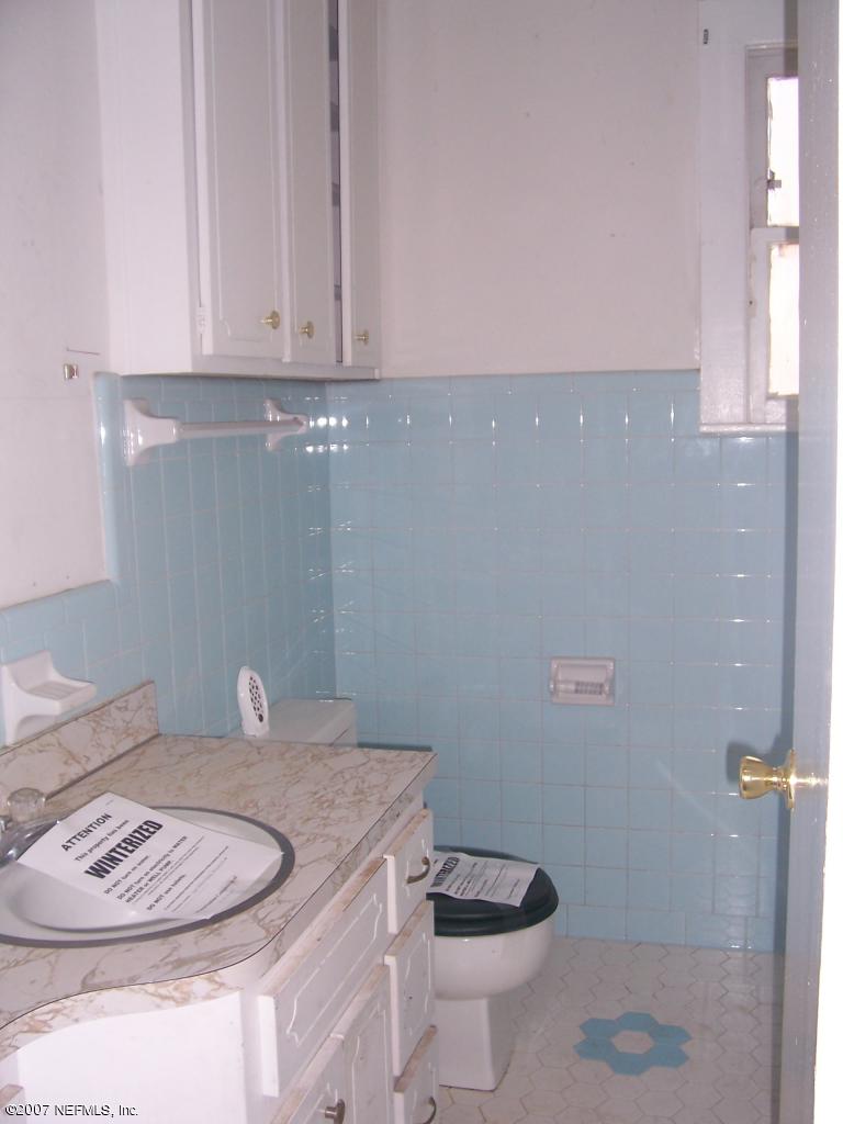 7657 Calvin Street Jacksonville, FL 32208 - Photo 6 of 8 a bathroom with a granite countertop sink a toilet and a mirror