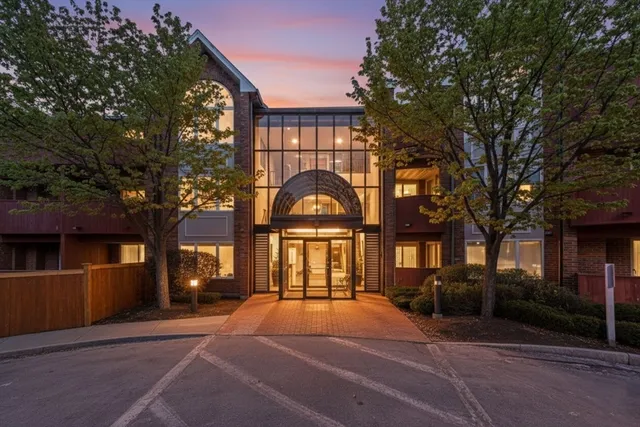a view of a brick house next to a yard with a large tree