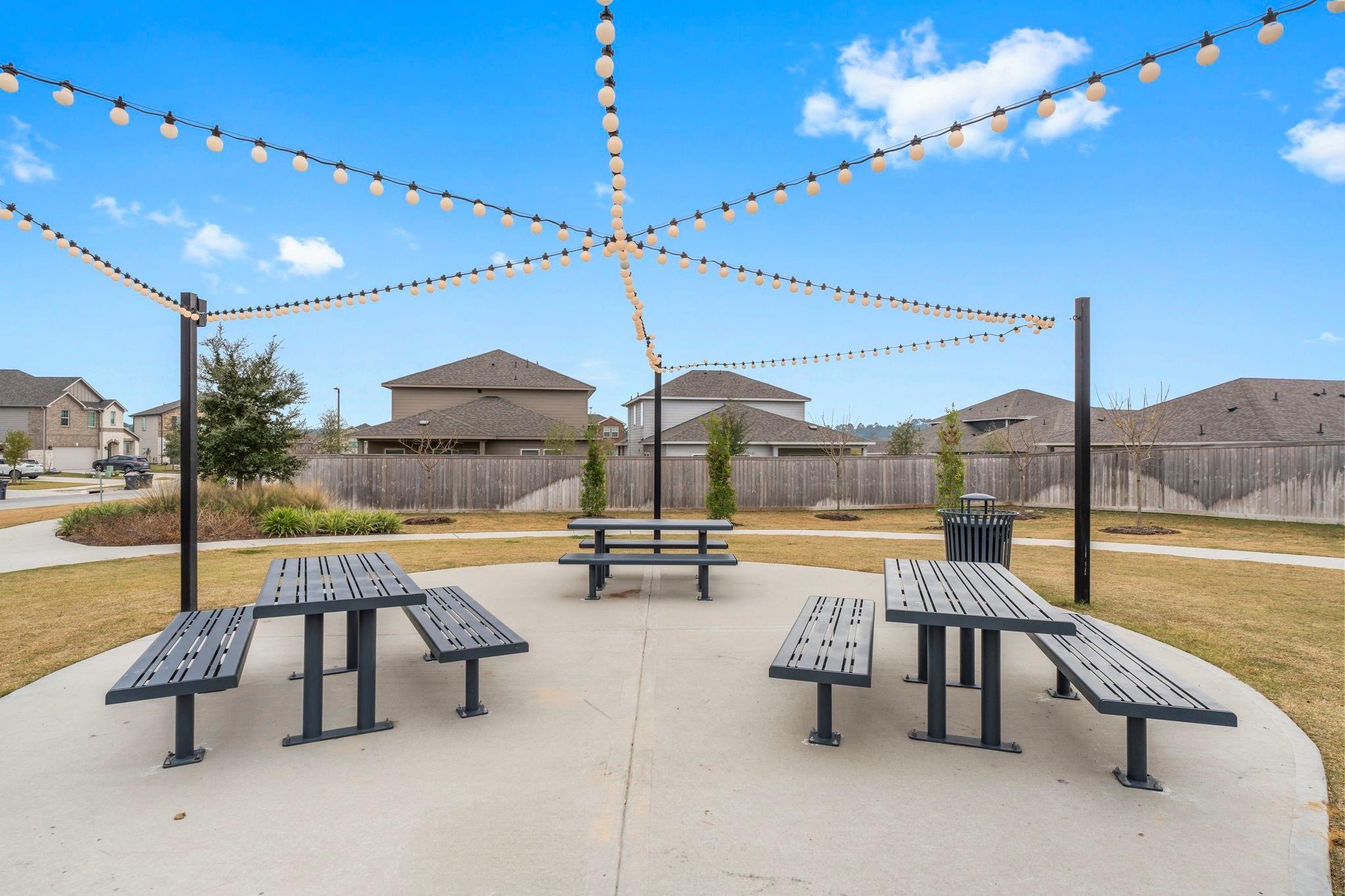 372 Sunrise Rnch Drive Montgomery, TX 77316 - Photo 23 of 32 Enjoy a community picnic area featuring several benches under string lights. It’s set in a suburban neighborhood, providing a welcoming space for outdoor gatherings.