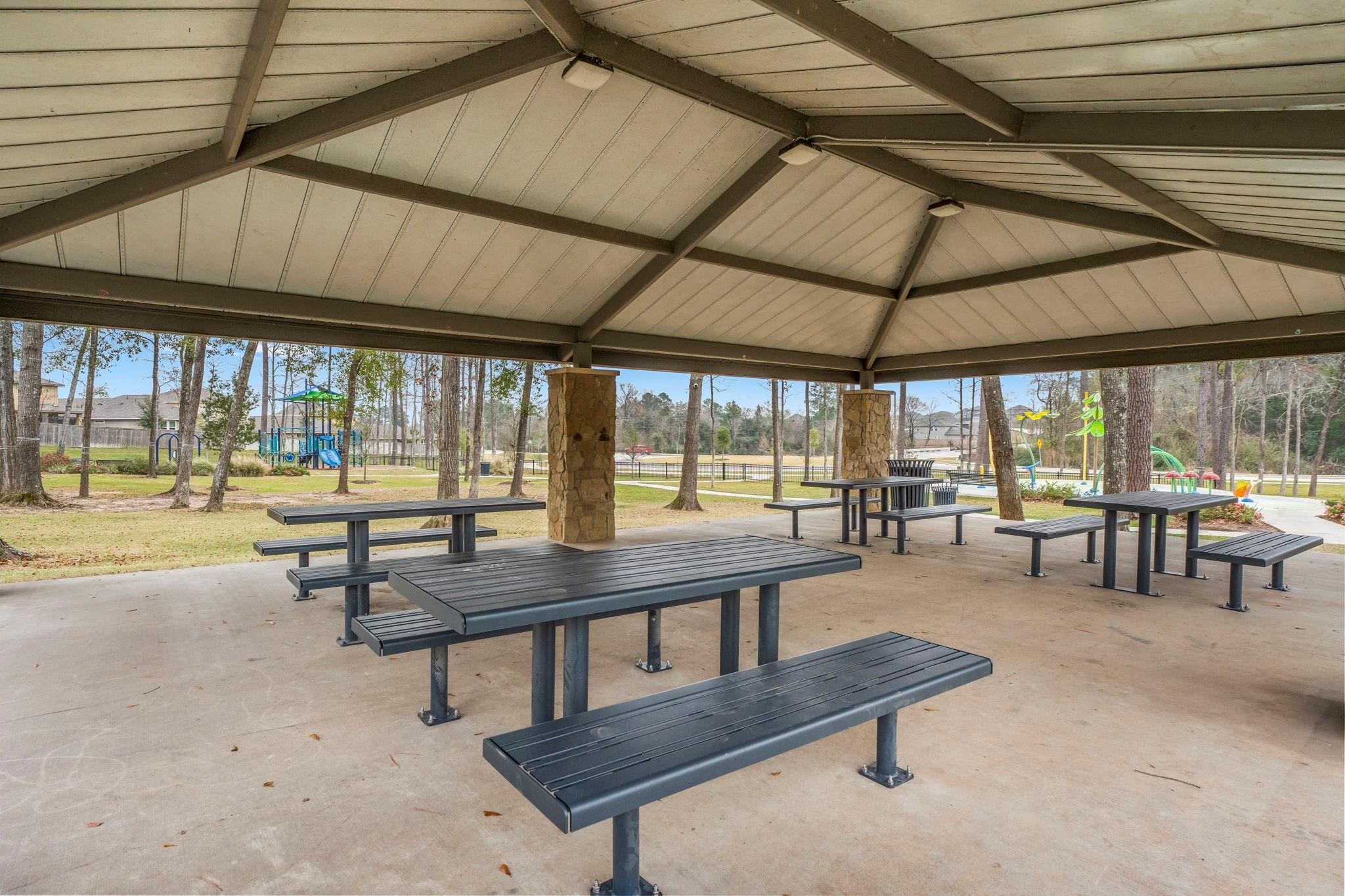372 Sunrise Rnch Drive Montgomery, TX 77316 - Photo 25 of 32 A covered outdoor pavilion with picnic tables, set in the park with trees and a playground in the background, ideal for gatherings and family activities.