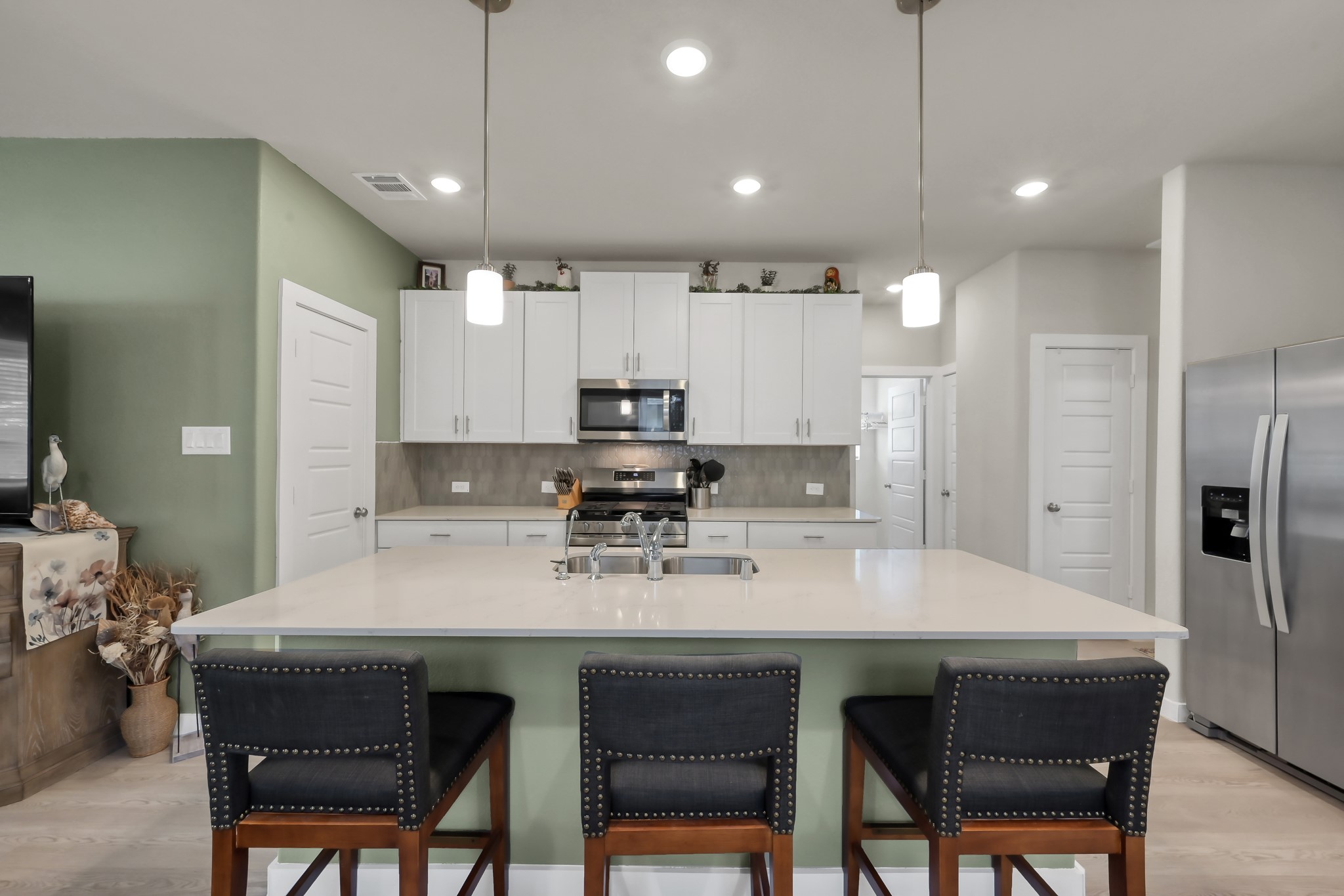 372 Sunrise Rnch Drive Montgomery, TX 77316 - Photo 4 of 32 Enjoy a spacious island with seating, modern pendant lighting, stainless steel appliances, and white cabinetry. It has a clean, contemporary design with an open layout.