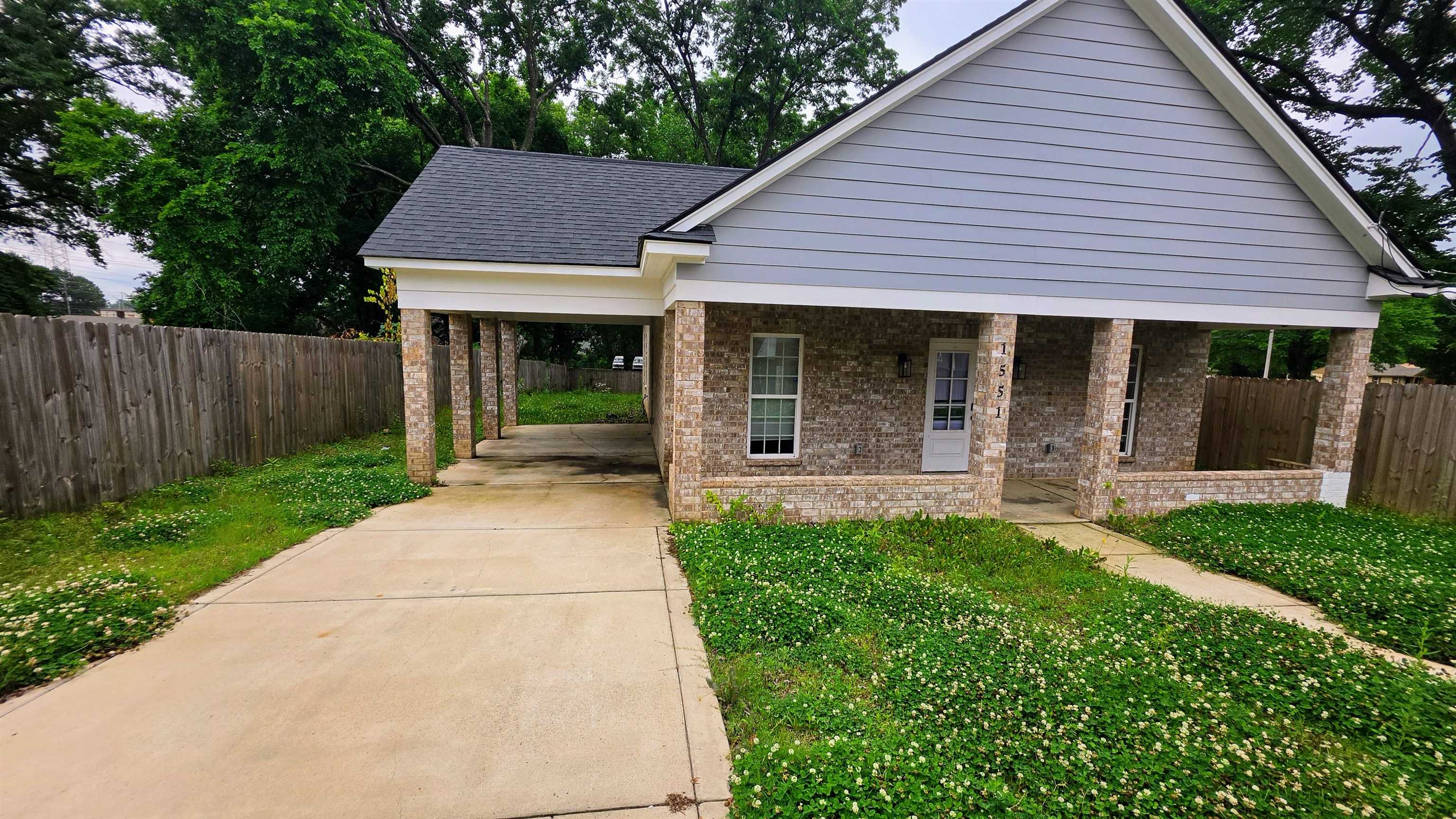 1551 Cane Road Memphis, TN 38106 - Photo 2 of 5 Brick and siding exterior featuring a covered front porch and a covered carport with a concrete driveway