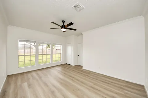 a view of empty room with wooden floor and ceiling fan