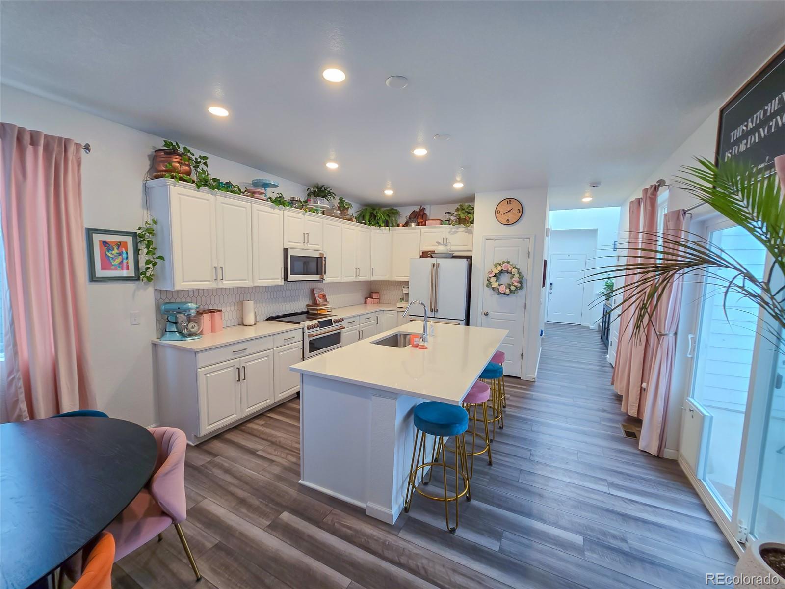 2084 Chambers Road Brighton, CO 80601 - Photo 16 of 50 a large kitchen with sink a refrigerator and white cabinets