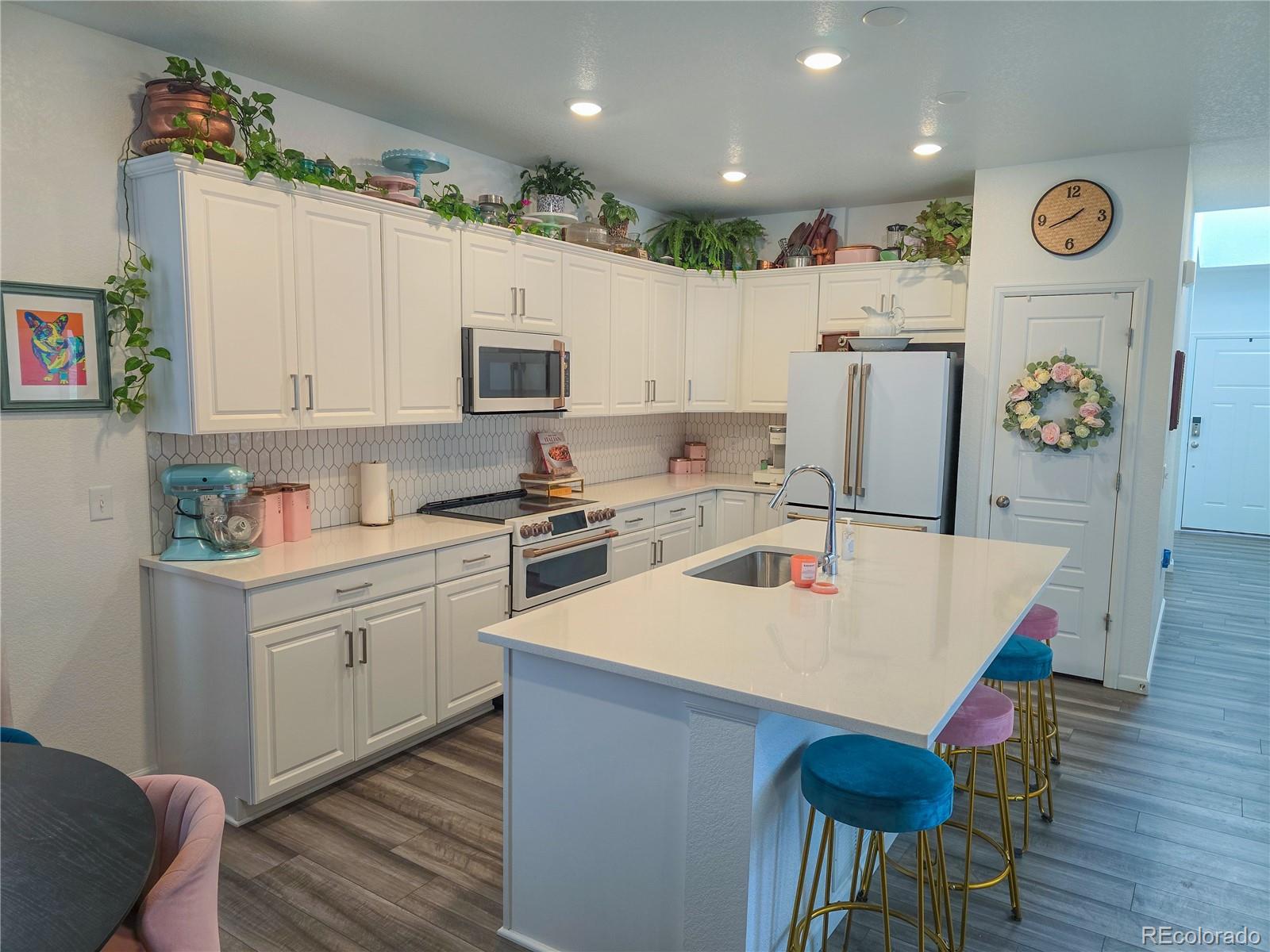 2084 Chambers Road Brighton, CO 80601 - Photo 17 of 50 a kitchen with a refrigerator a stove and a dining table with wooden floor
