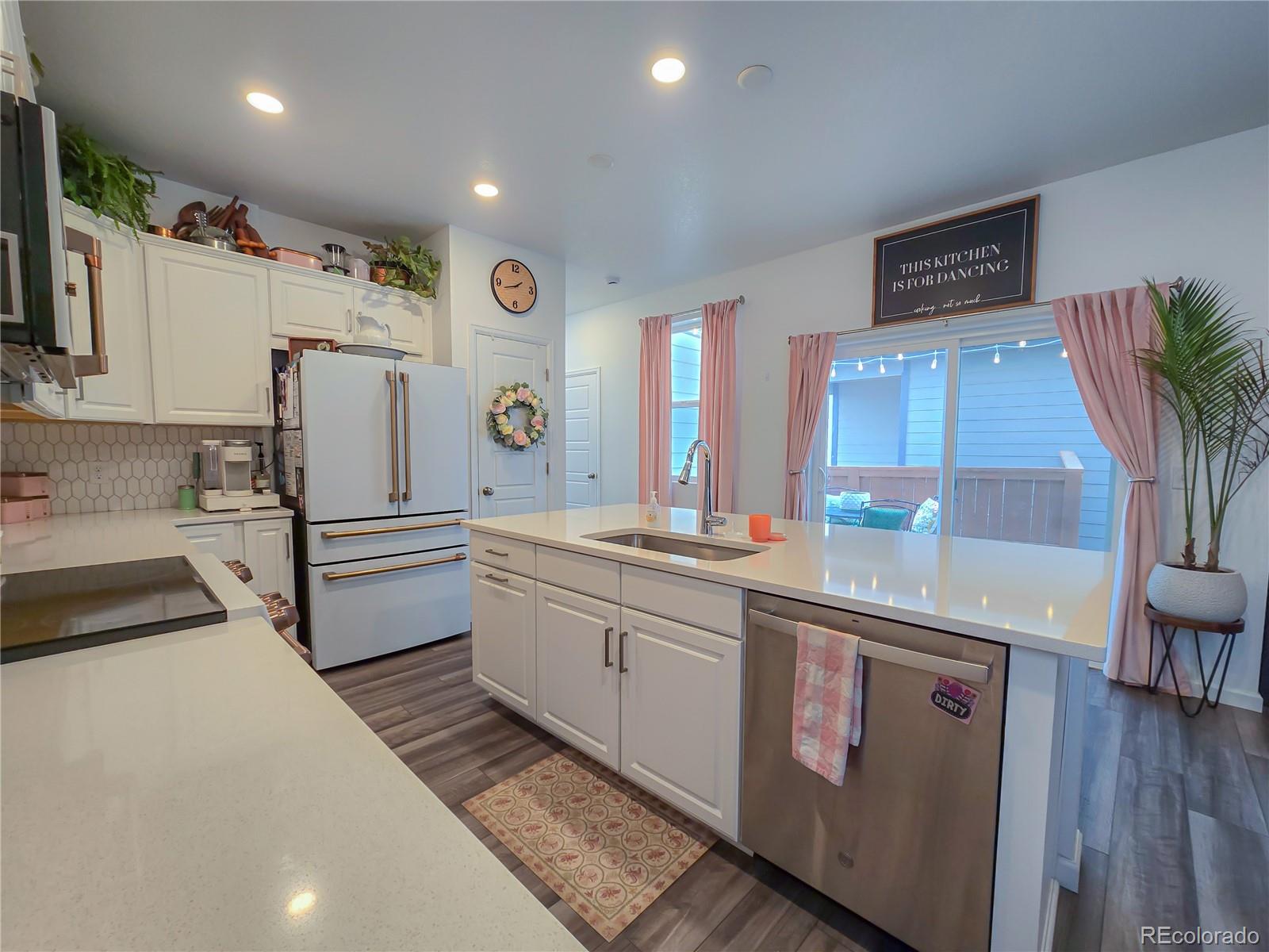 2084 Chambers Road Brighton, CO 80601 - Photo 19 of 50 a kitchen with stainless steel appliances a sink cabinets and wooden floor