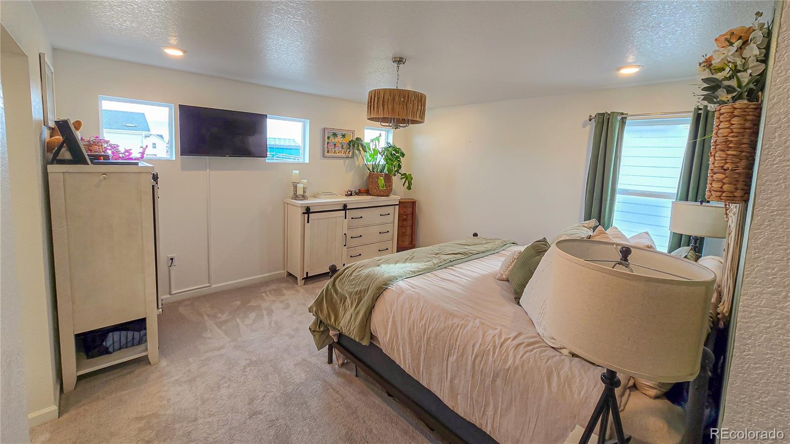 2084 Chambers Road Brighton, CO 80601 - Photo 28 of 50 a bedroom with a bed dresser and a flat screen tv
