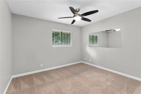 an empty room with a chandelier fan and windows