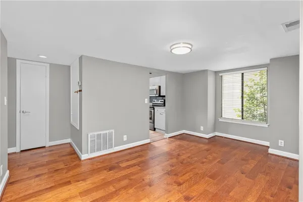 a view of empty room with wooden floor and fan