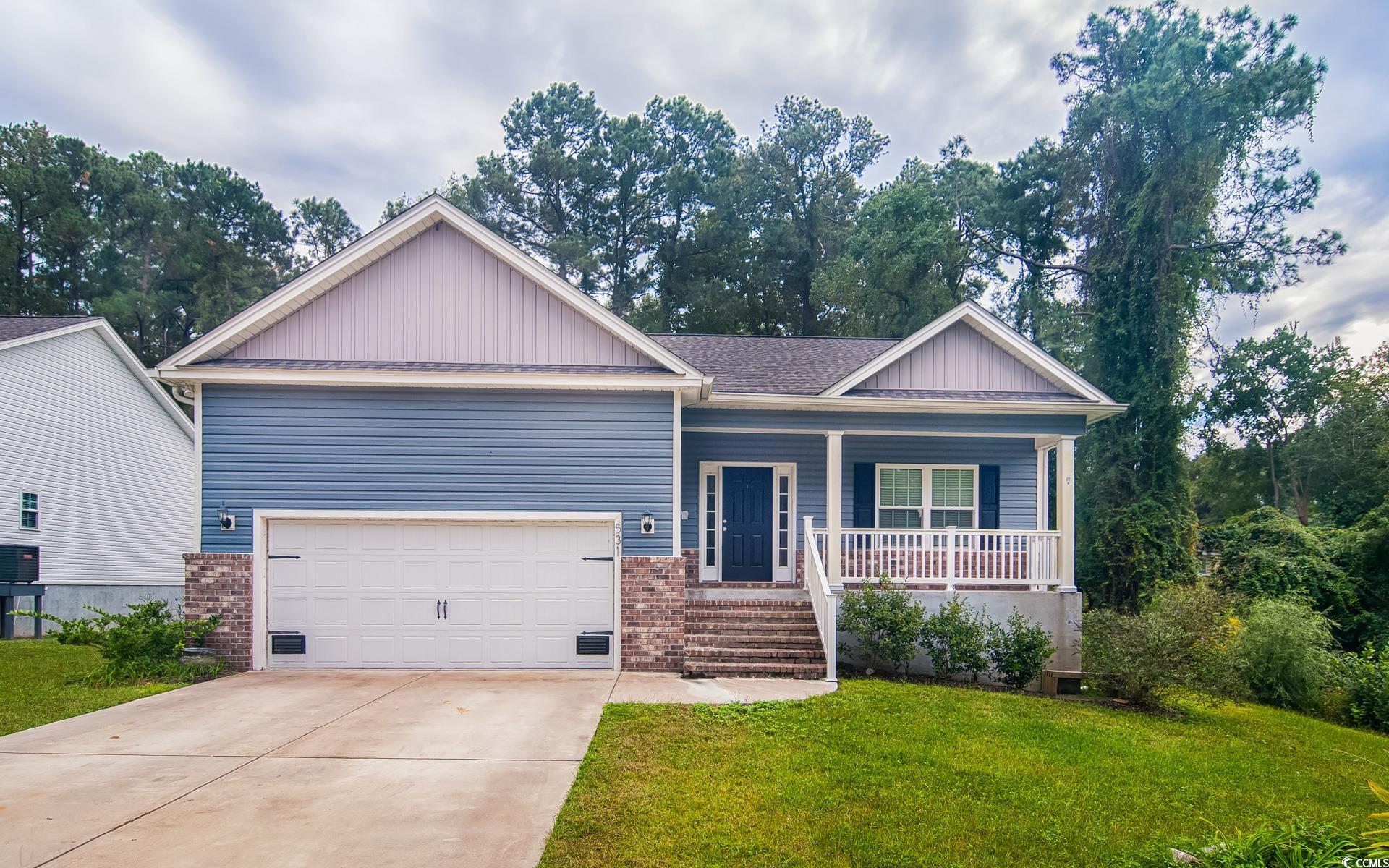 View of front of home with brick siding, a porch, a shingled roof, driveway, and a front yard