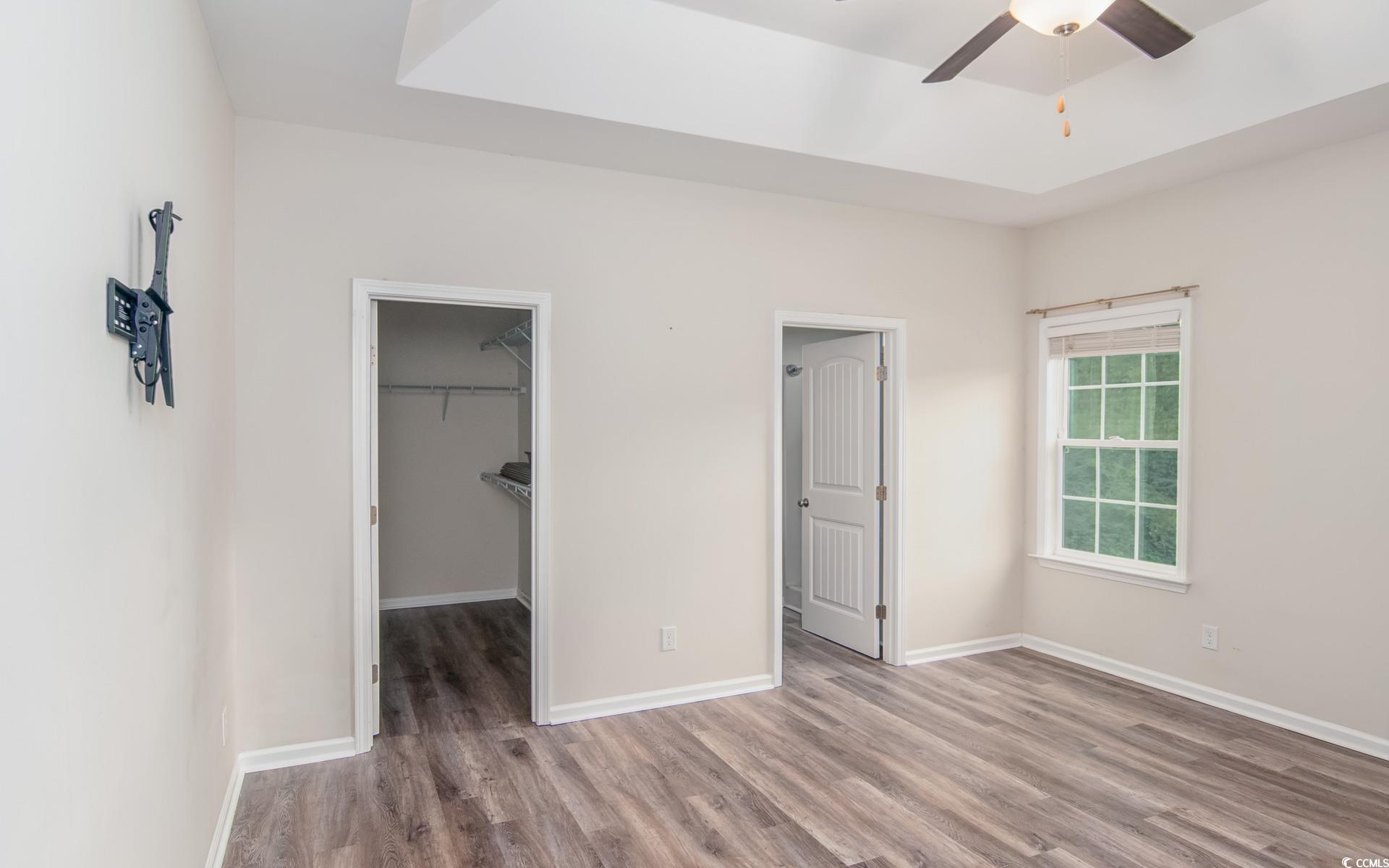 531 Charlton Boulevard Georgetown, SC 29440 - Photo 10 of 19 Unfurnished bedroom featuring a walk in closet, wood finished floors, a raised ceiling, and a ceiling fan