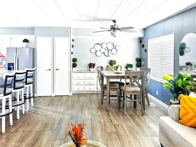 a view of a dining room and livingroom with furniture wooden floor a rug a potted plant and a chandelier
