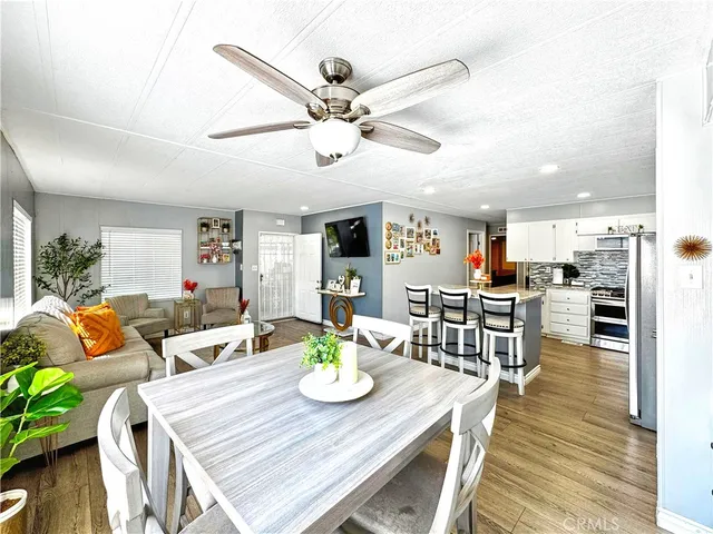 a living room with furniture kitchen view and a wooden floor