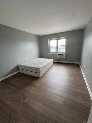 a spacious bedroom with a bed and wooden floor