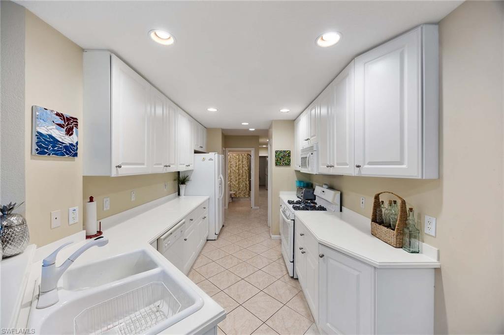 3955 Deer Crossing Court, Unit 103 Naples, FL 34114 - Photo 14 of 40 a large white kitchen with stainless steel appliances granite countertop a sink and cabinets