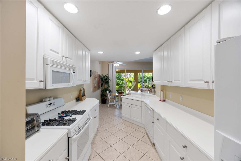 3955 Deer Crossing Court, Unit 103 Naples, FL 34114 - Photo 15 of 40 a kitchen with white cabinets and appliances