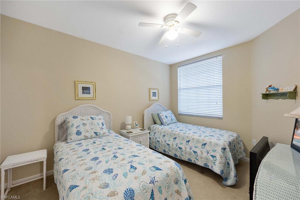 3955 Deer Crossing Court, Unit 103 Naples, FL 34114 - Photo 24 of 40 a bedroom with two beds and a chandelier