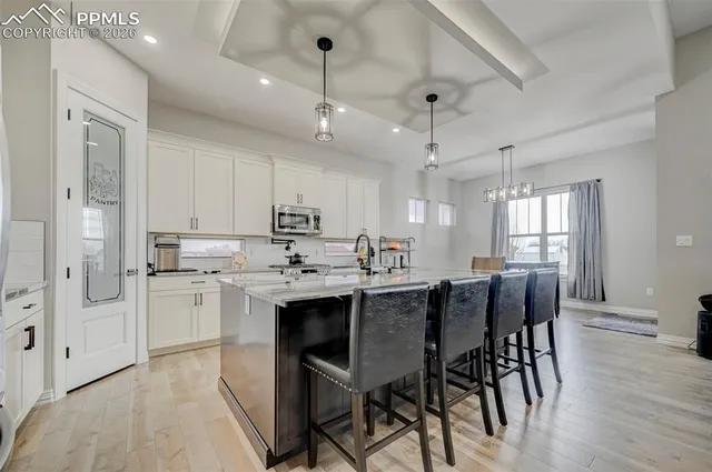 a kitchen with stainless steel appliances kitchen island granite countertop a dining table chairs and white cabinets