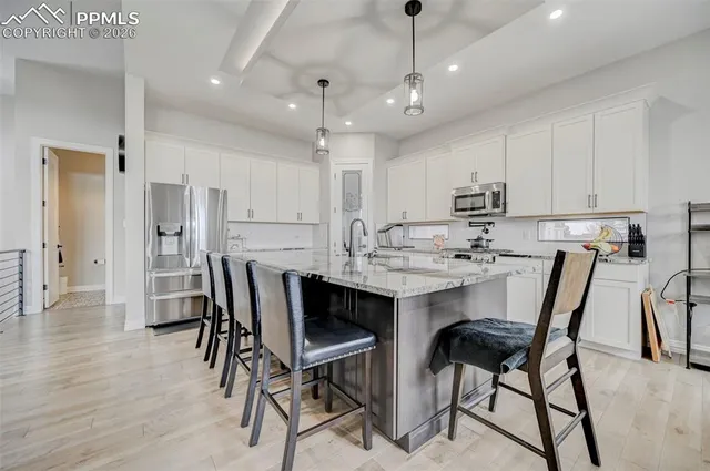 a kitchen with stainless steel appliances kitchen island granite countertop a dining table chairs and white cabinets