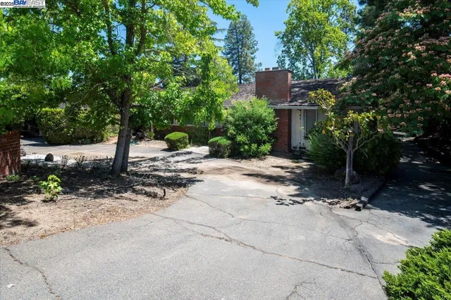 a backyard of a house with table and chairs with wooden fence and plants