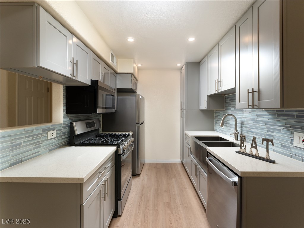 3318 North Decatur Boulevard, Unit 2149 Las Vegas, NV 89130 - Photo 3 of 26 Kitchen featuring tasteful backsplash, stainless steel appliances, light wood-style flooring, light stone counters, and recessed lighting