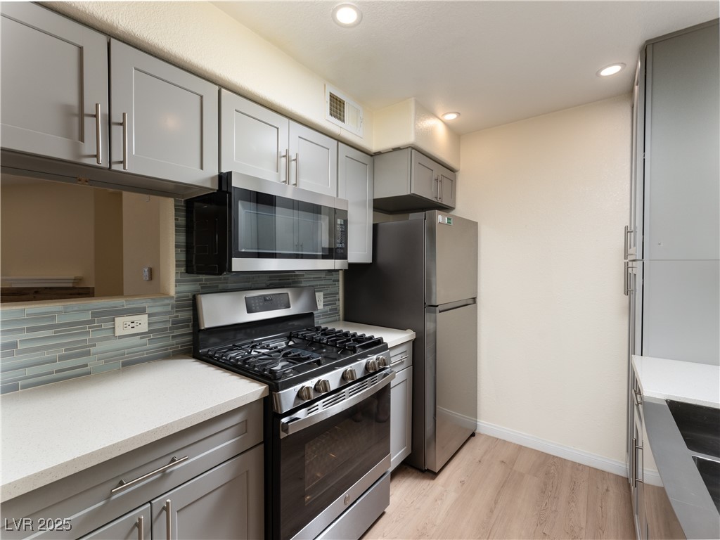 3318 North Decatur Boulevard, Unit 2149 Las Vegas, NV 89130 - Photo 4 of 26 Kitchen featuring appliances with stainless steel finishes, gray cabinets, light wood-style floors, recessed lighting, and tasteful backsplash