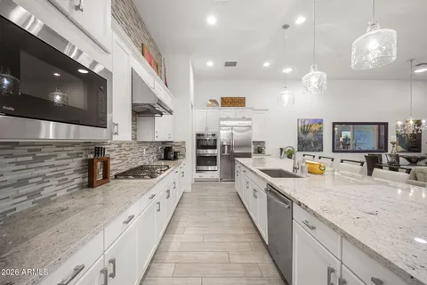 a large kitchen with stainless steel appliances kitchen island granite countertop a large counter top and a stove