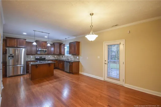 a large kitchen with stainless steel appliances granite countertop a refrigerator a oven a stove and a wooden floors