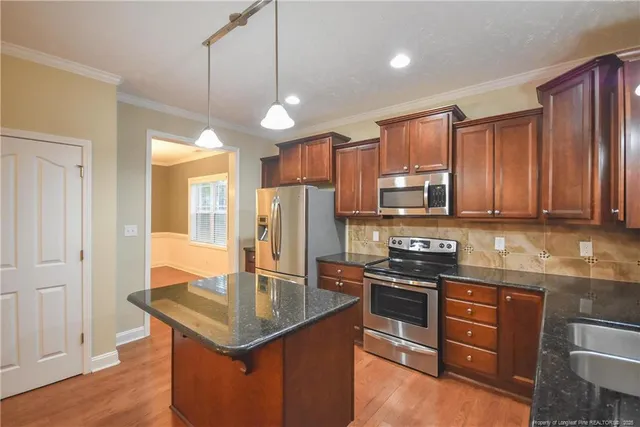 a kitchen with stainless steel appliances granite countertop a stove refrigerator and cabinets