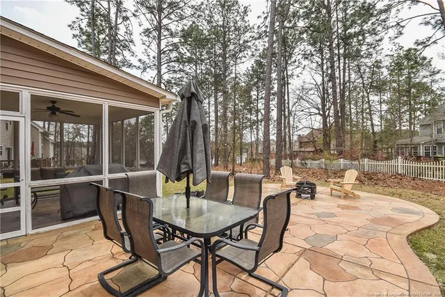 a view of a patio with a dining table and chairs with wooden floor and fence