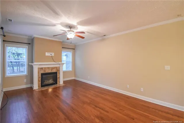 an empty room with fireplace wooden floor and windows