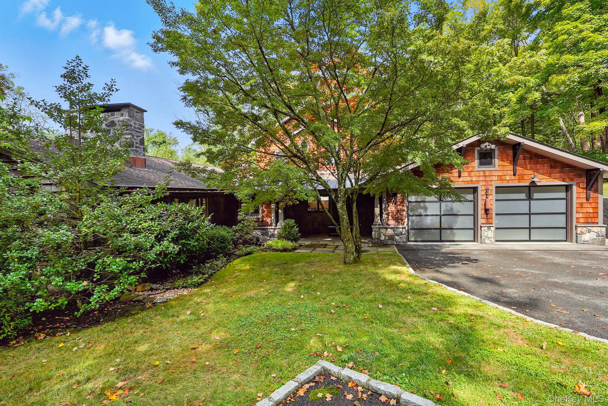 View of front of house with stone siding, a front lawn, driveway, and a chimney