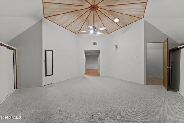 an empty room with chandelier fan and windows
