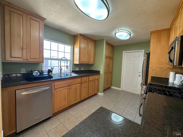 a kitchen with stainless steel appliances granite countertop a sink a stove cabinets and a window